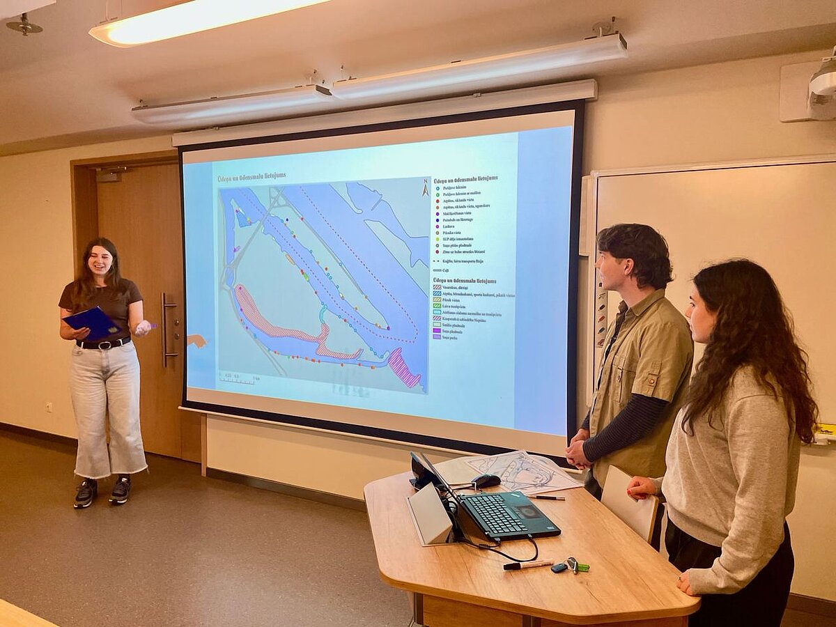 The picture shows the classroom where the presentation is taking place. You can see a map slide above which the title "Use of waters and waterfronts" is displayed. Presented by three students. The picture shows the classroom where the presentation is taking place. You can see a map slide above which the title "Use of waters and waterfronts" is displayed. Presented by three students.